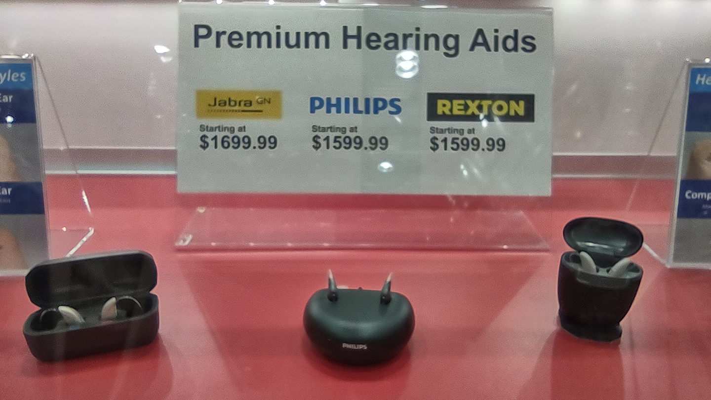 Three hearing aid models on display at Costco with sign reading 'Premium Hearing Aids'